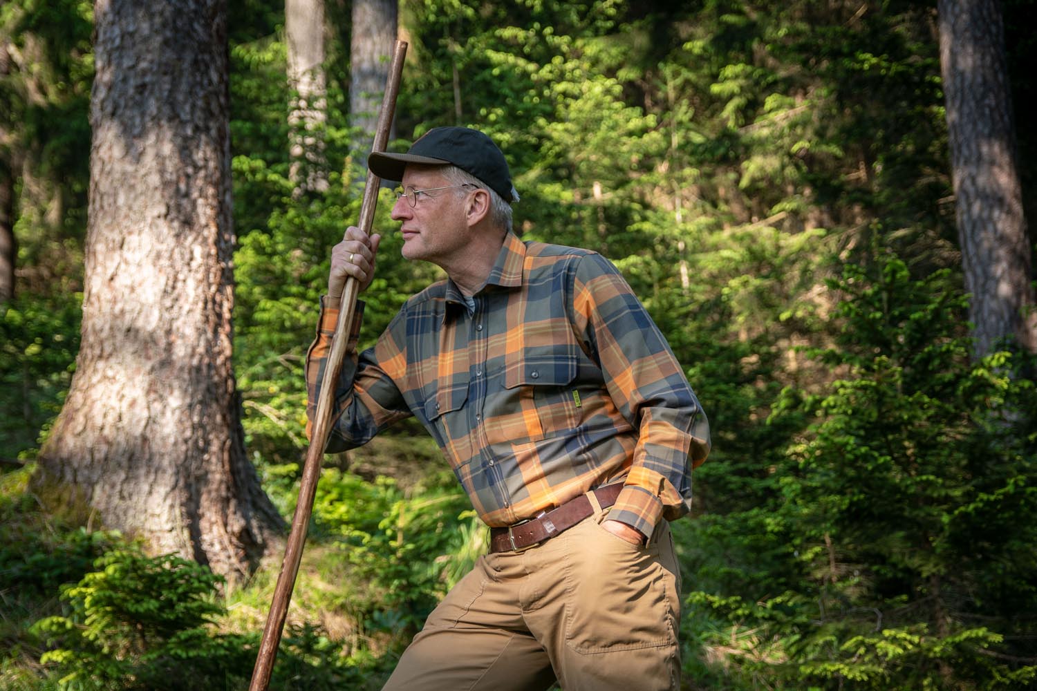 Jäger in sonnigem Wald Jäger mit Karohemd schaut in Wald