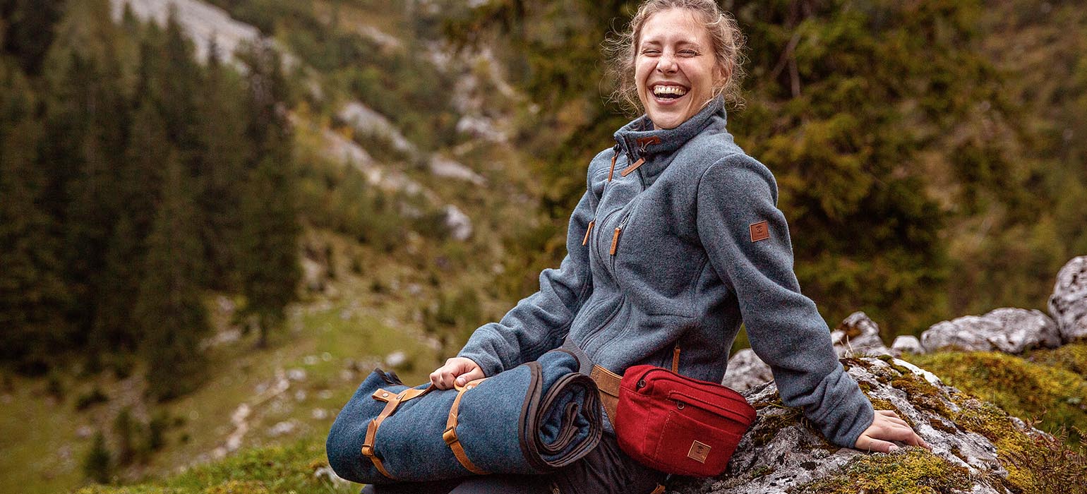 Lachende Wanderin auf Felsen Bergwanderer mit Wolldecke